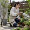 ホースリールのシャワー水流で庭の花や鉢植えに水やりする女性