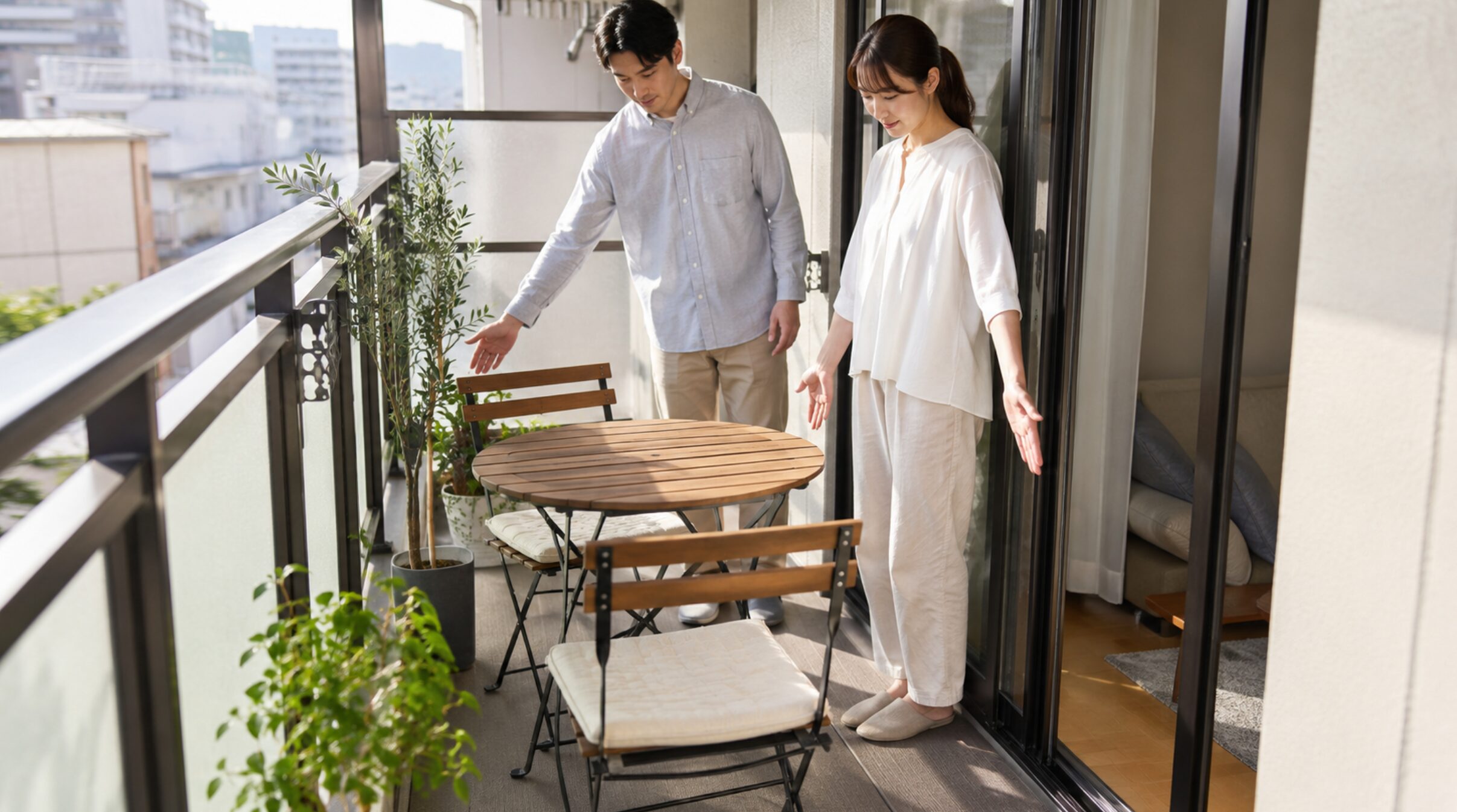 狭いベランダで2人用ガーデンテーブルと椅子の設置スペースを確認する日本人夫婦