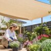 ガーデニング用シェードの下で鉢植えの花を手入れする日本人女性