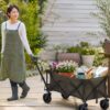 花苗や園芸道具を載せたガーデニングワゴンを庭で引く女性