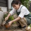低い屋外蛇口で植木鉢と移植ごてを洗う日本人女性