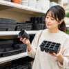 園芸店で育苗ポットと育苗トレーを比較して選ぶ女性