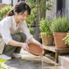 蚊の発生源を減らすため植木鉢の受け皿にたまった水を捨てる女性