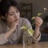 水栽培で葉が小さくつるが細く伸びたポトスを確認する女性